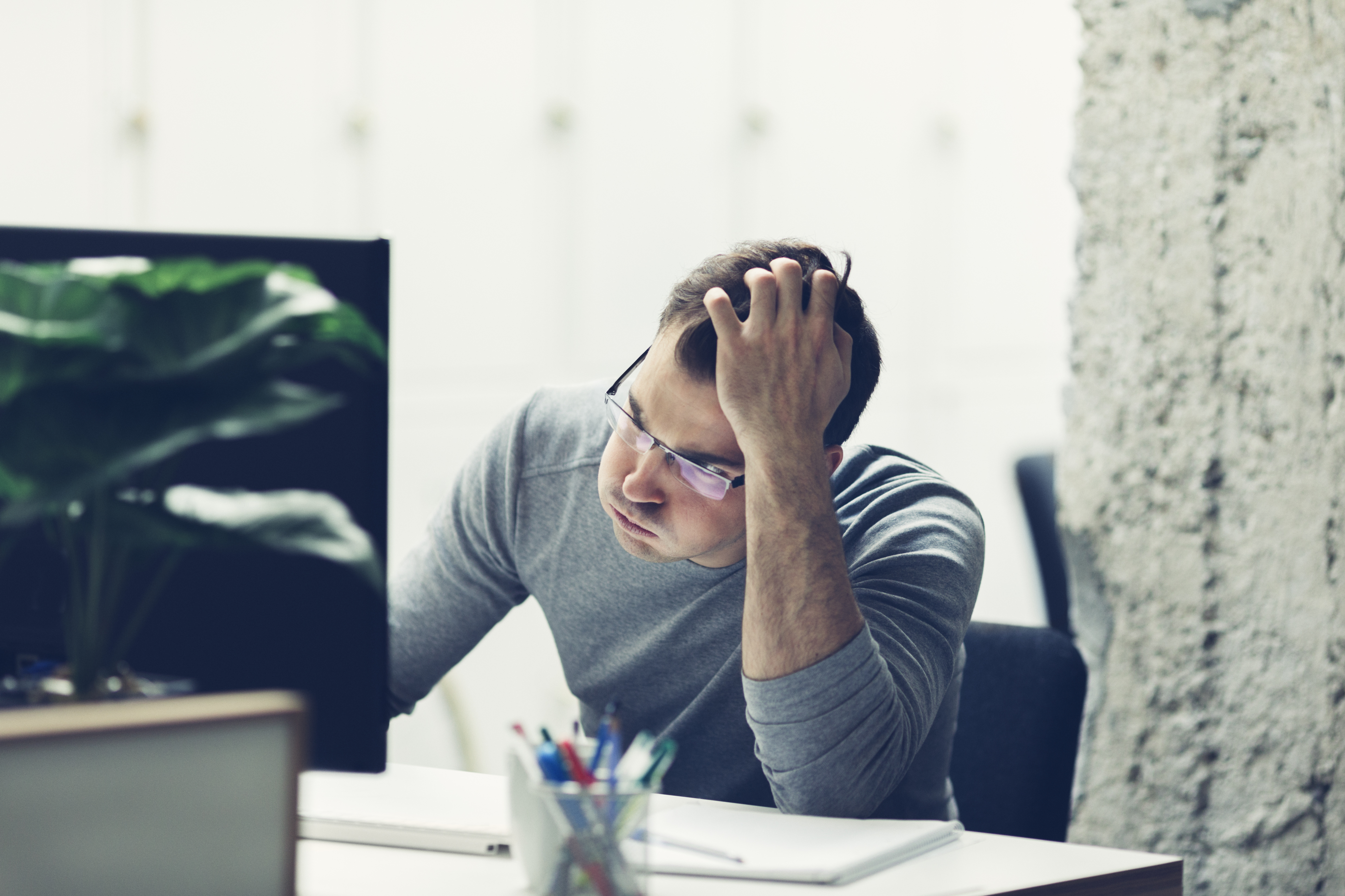 Worried businessman working in office. Fearful expression and holding his hair with hand.